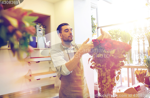 Image of smiling florist man with roses at flower shop