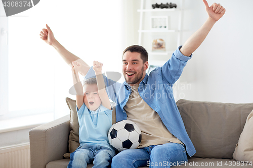 Image of father and son watching soccer on tv at home