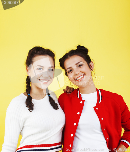 Image of lifestyle people concept: two pretty young school teenage girls having fun happy smiling on yellow background 