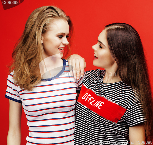 Image of two best friends teenage girls together having fun, posing emotional on red background, besties happy smiling, lifestyle people concept close up