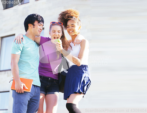 Image of cute group of teenages at the building of university with books huggings, back to school