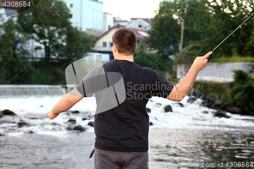 Image of Young man with fishing rod fishing at a river in Bavaria