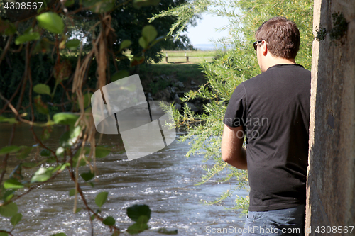 Image of Young man with fishing rod fishing at a river