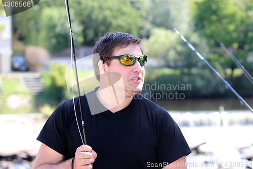 Image of Young man with fishing rod fishing at a river in Bavaria