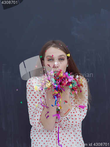 Image of woman blowing confetti in the air isolated over gray