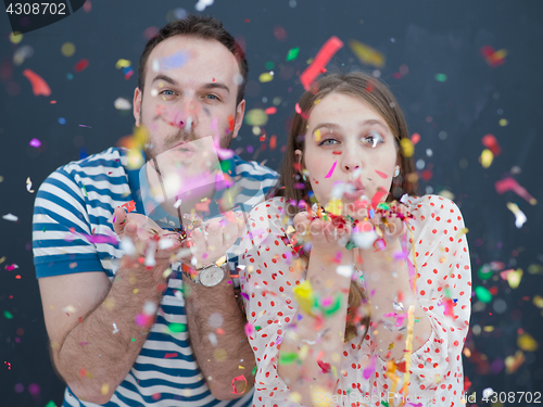 Image of couple blowing confetti in the air isolated over gray