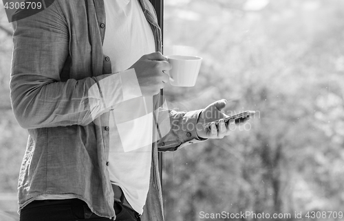 Image of Clouseup of young man using mobile and drinking coffe