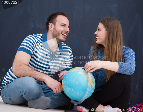 Image of couple in casual clothing investigating globe