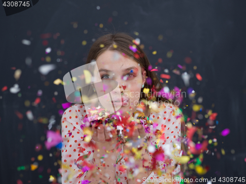 Image of woman blowing confetti in the air isolated over gray