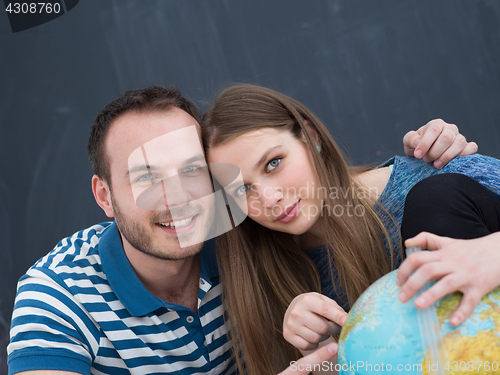 Image of couple in casual clothing investigating globe