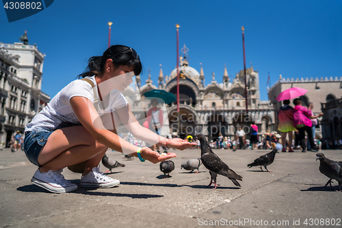 Image of Woman tourist feeding pigeons in the square - St. Marks Square -