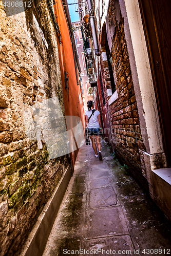 Image of Woman walks through the narrow streets of Venice