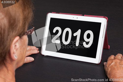 Image of Senior lady relaxing and her tablet - 2019