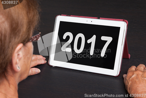 Image of Senior lady relaxing and her tablet - 2017