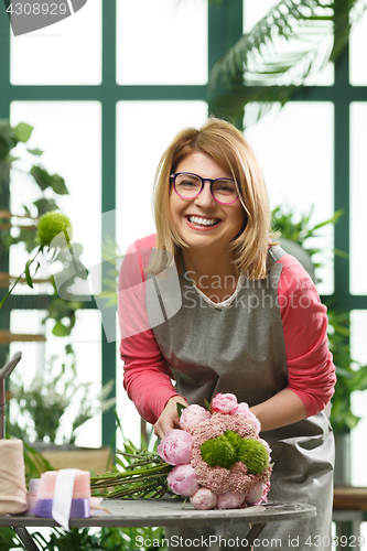 Image of Florist with glasses makes bouquet