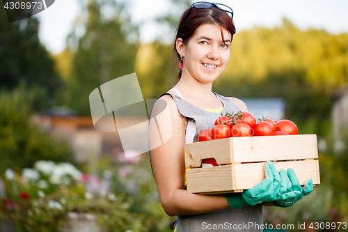 Image of Brunette holding box with tomatoes
