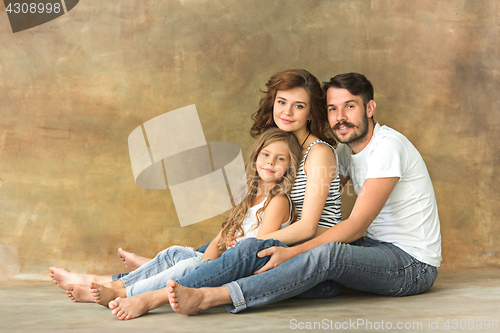 Image of Pregnant mother with teen daughter and husband. Family studio portrait over brown background