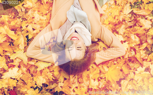 Image of beautiful happy woman lying on autumn leaves