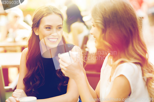 Image of smiling young women with coffee cups at cafe