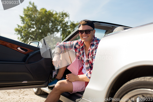 Image of happy young man sitting in convertible car