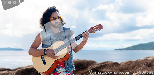 Image of hippie man playing guitar over sea