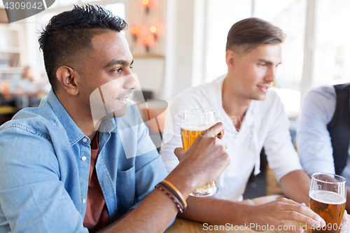 Image of happy male friends drinking beer at bar or pub