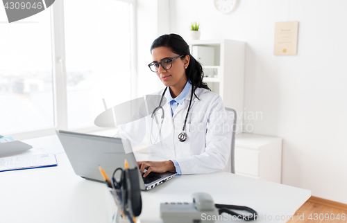 Image of female doctor typing on laptop at hospital