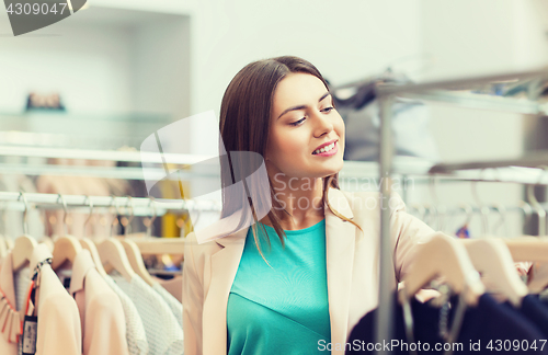 Image of happy young woman choosing clothes in mall