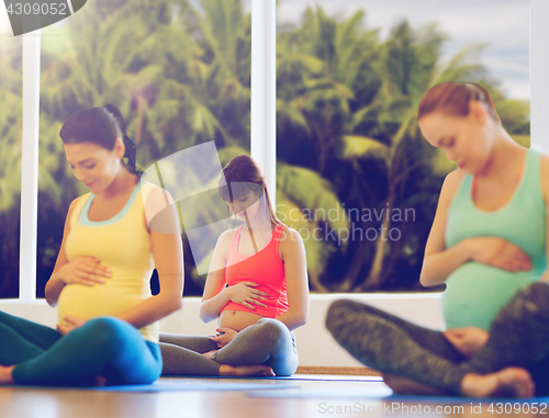 Image of happy pregnant women exercising yoga in gym