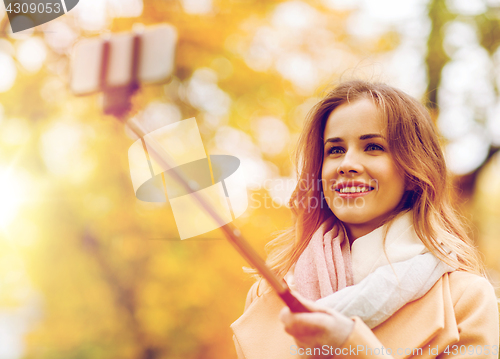 Image of woman taking selfie by smartphone in autumn park