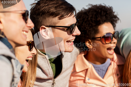 Image of happy teenage friends in shades laughing outdoors