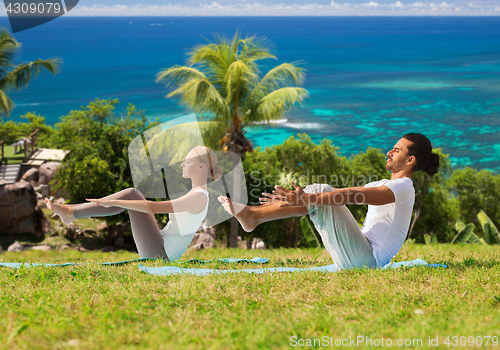 Image of couple making yoga half-boat pose outdoors