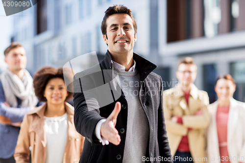 Image of man giving hand for handshake on city street