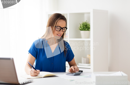 Image of woman with calculator and notebook at office