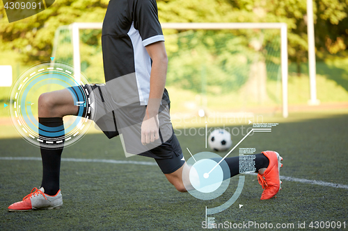 Image of soccer player stretching leg on field football