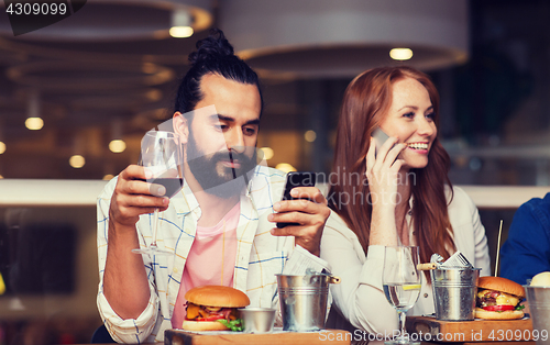 Image of happy friends with smartphones at restaurant