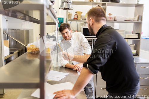 Image of chef and cook with grocery list at kitchen
