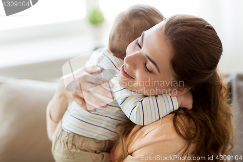 Image of happy young mother hugging little baby at home