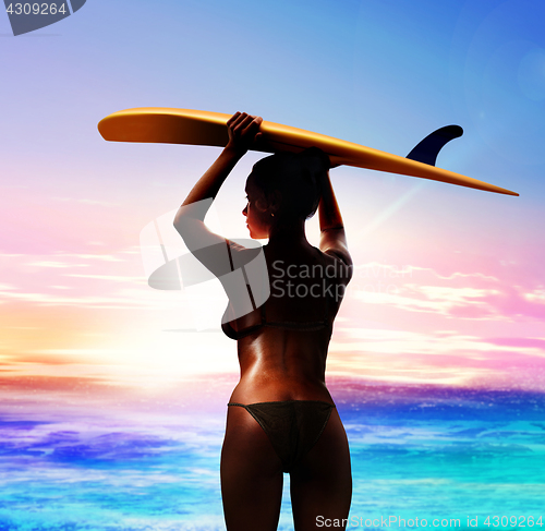 Image of surfer with surfboard at sunrise