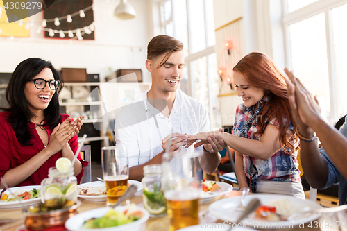 Image of happy man doing proposal to woman at restaurant