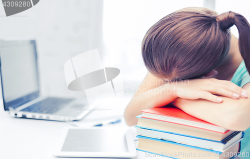 Image of tired student sleeping on stock of books