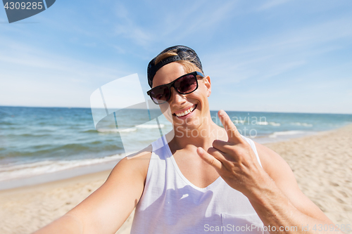 Image of man in sunglasses taking selfie on summer beach