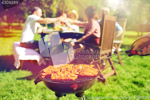 Image of man cooking meat on barbecue grill at summer party
