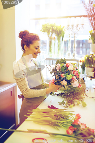 Image of smiling florist woman making bunch at flower shop