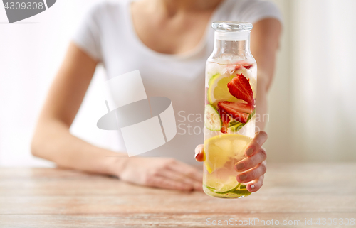 Image of close up of woman with fruit water in glass bottle