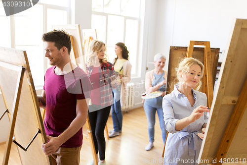 Image of artists with brushes painting at art school