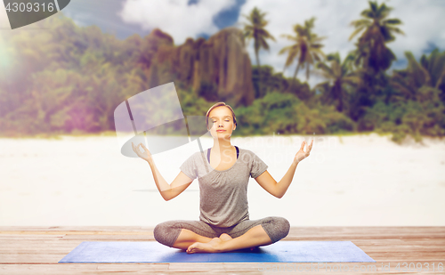 Image of woman doing yoga meditation in lotus pose on beach