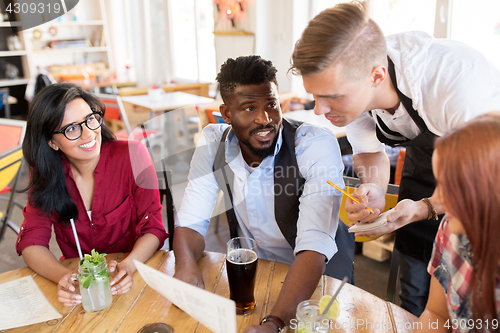 Image of waiter and friends with menu and drinks at bar