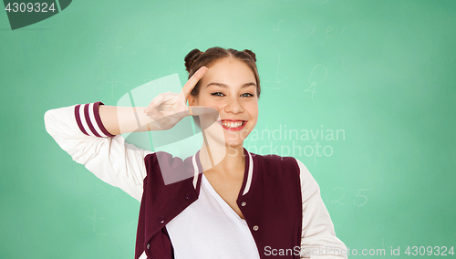 Image of happy student girl showing peace sign over green