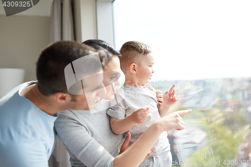 Image of happy family looking through window at home